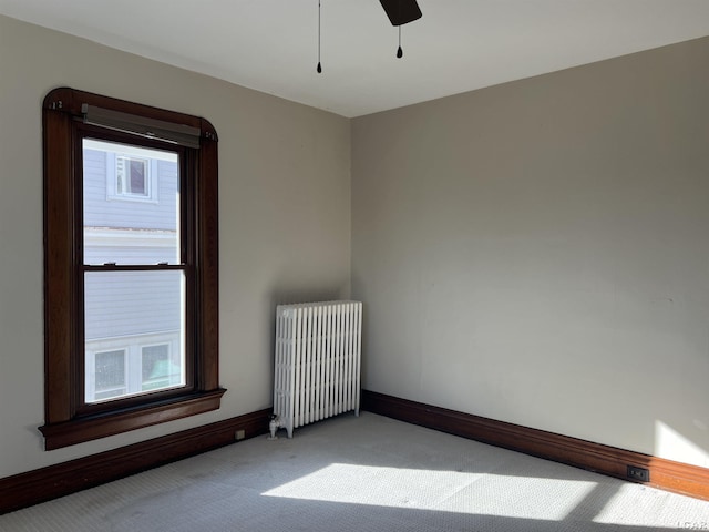 carpeted spare room with a wealth of natural light, ceiling fan, and radiator