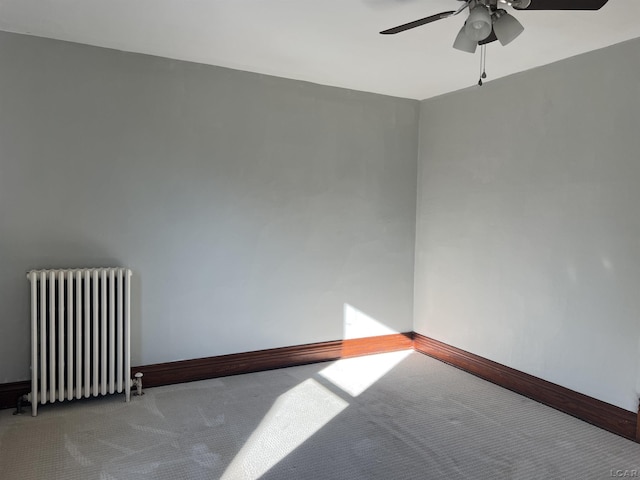 carpeted empty room featuring ceiling fan and radiator heating unit