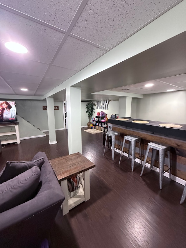 game room with a paneled ceiling and dark wood-type flooring