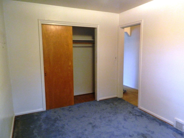 unfurnished bedroom with dark carpet and a closet