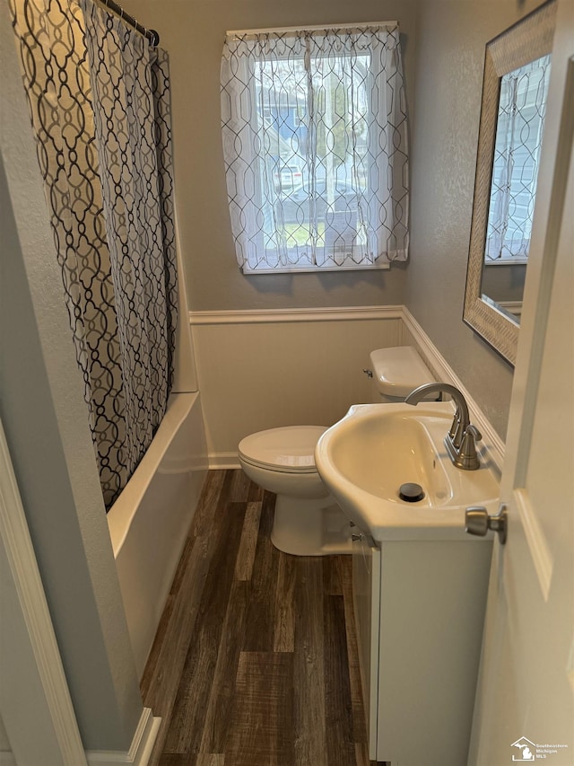 full bathroom featuring hardwood / wood-style flooring, toilet, shower / bathtub combination with curtain, and sink