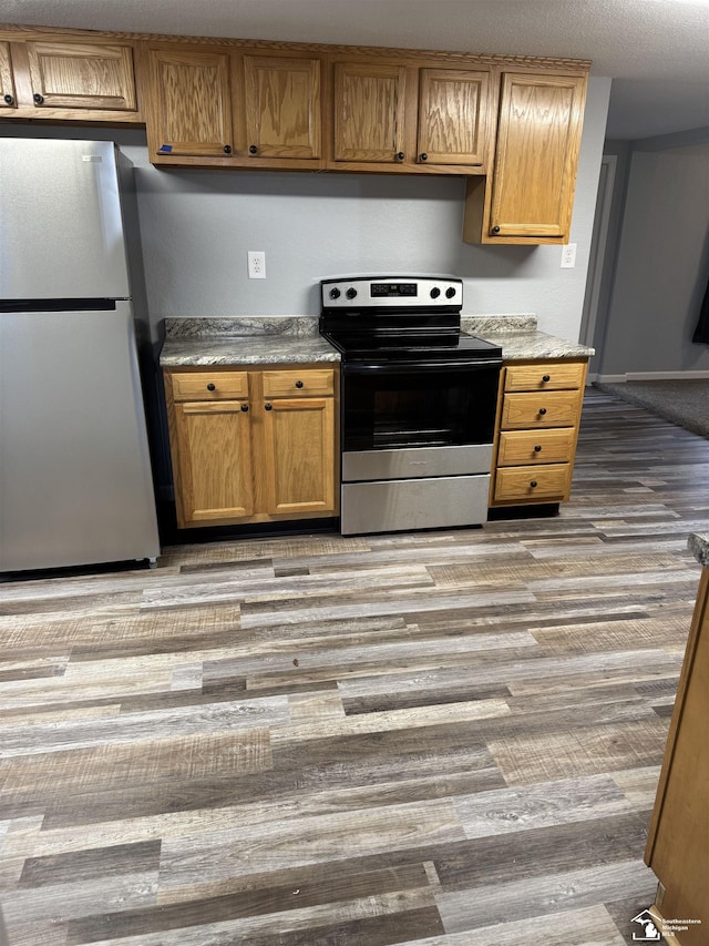 kitchen featuring refrigerator, stainless steel electric range, and light wood-type flooring