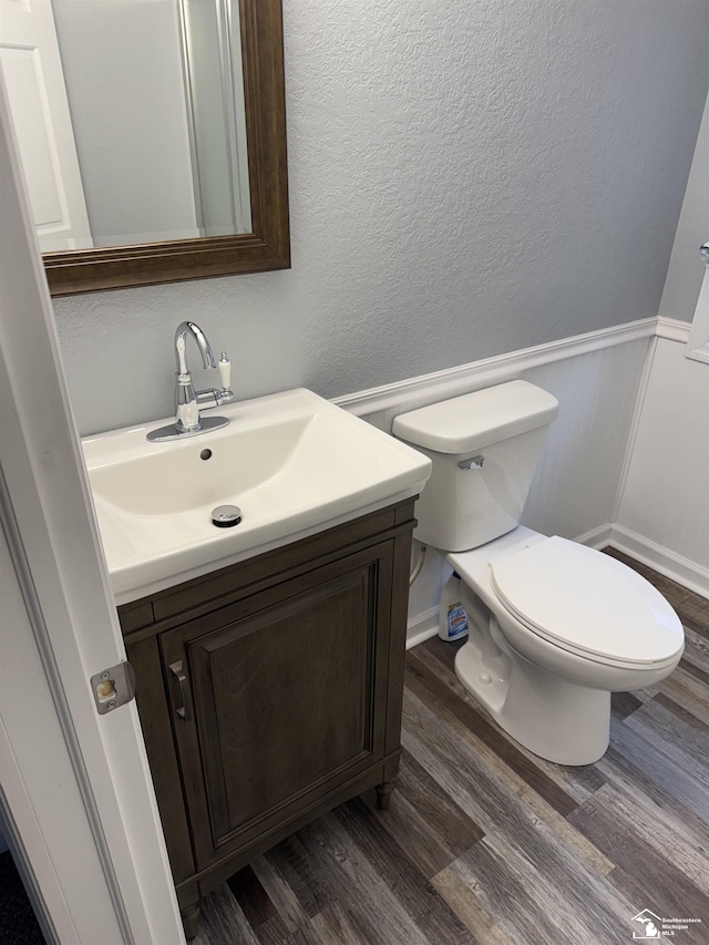 bathroom with wood-type flooring, vanity, and toilet