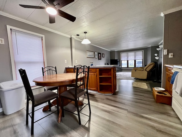 dining room with ceiling fan, ornamental molding, and light hardwood / wood-style flooring