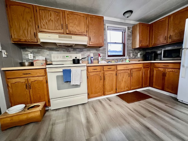 kitchen with sink, crown molding, light hardwood / wood-style floors, white appliances, and decorative backsplash