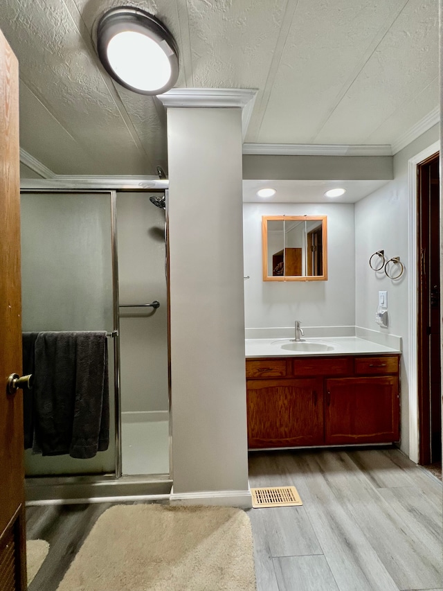 bathroom with a shower with door, vanity, wood-type flooring, and ornamental molding