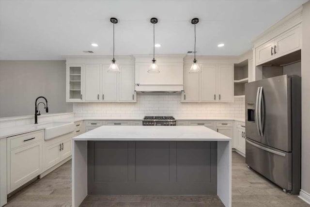 kitchen with stainless steel fridge, stove, tasteful backsplash, sink, and hanging light fixtures