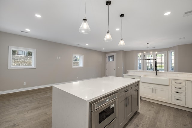 kitchen featuring a center island, sink, hanging light fixtures, light wood-type flooring, and a notable chandelier