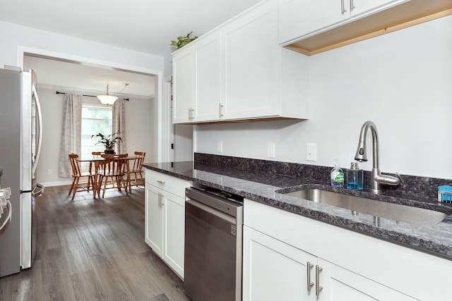 kitchen featuring white cabinets, stainless steel appliances, dark stone countertops, and sink