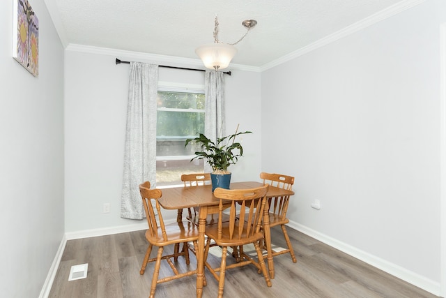 dining space with hardwood / wood-style floors, crown molding, and a textured ceiling