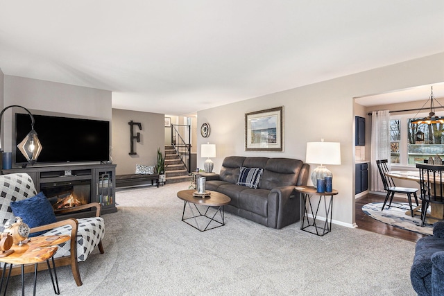 carpeted living area with stairs, baseboards, and a glass covered fireplace