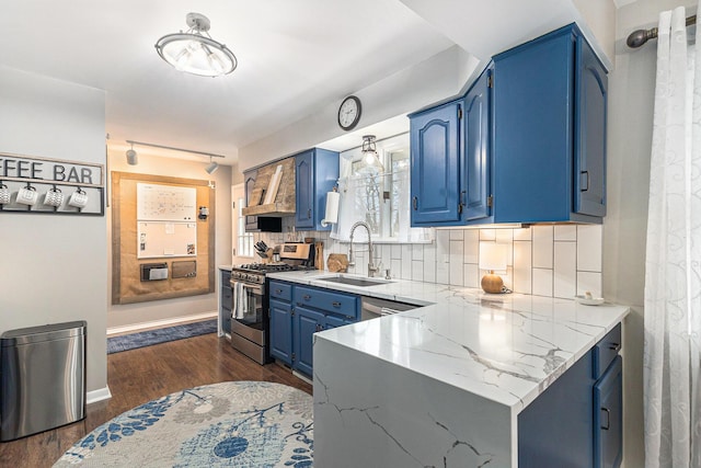 kitchen with blue cabinetry, a sink, light stone countertops, stainless steel gas range, and a peninsula