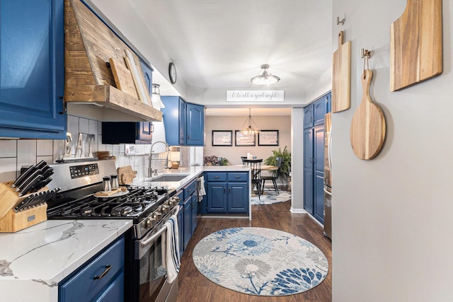 kitchen with stainless steel appliances, decorative light fixtures, a sink, and blue cabinetry