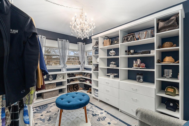 spacious closet with light wood-style flooring and a notable chandelier