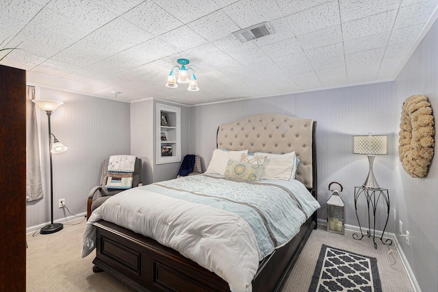 carpeted bedroom with baseboards, visible vents, and ornamental molding