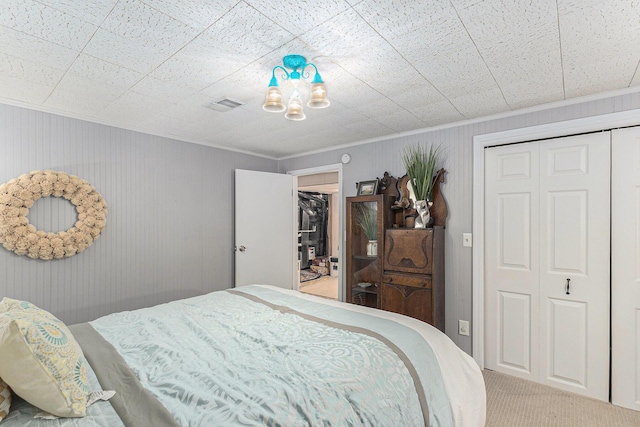 carpeted bedroom with a closet, visible vents, and crown molding