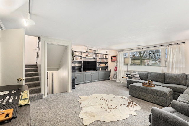 living room with rail lighting, carpet flooring, and stairway