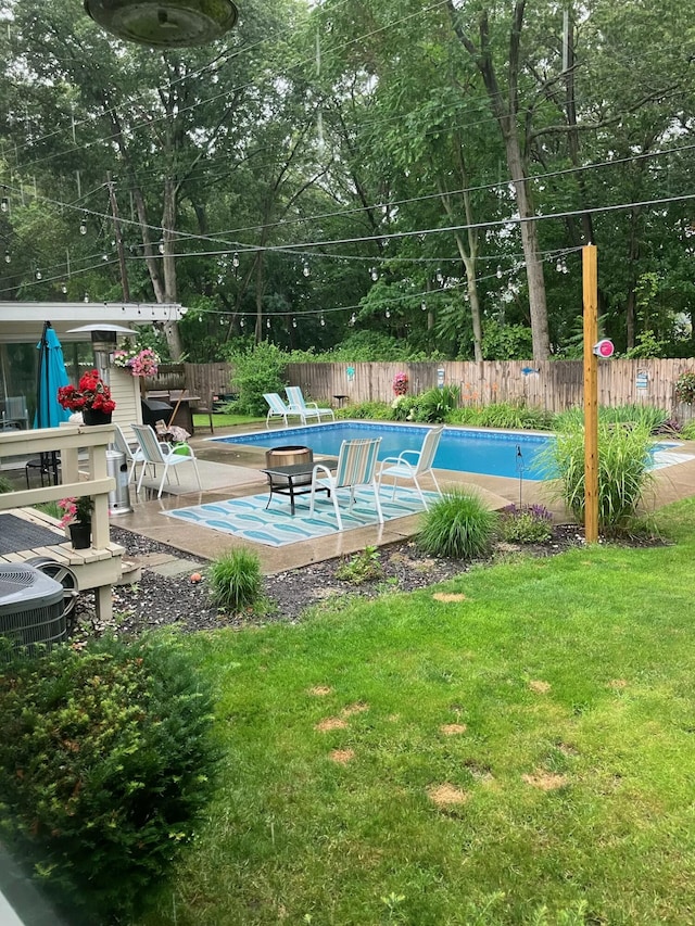 view of pool with a fenced in pool, a yard, an outdoor fire pit, central AC, and a fenced backyard