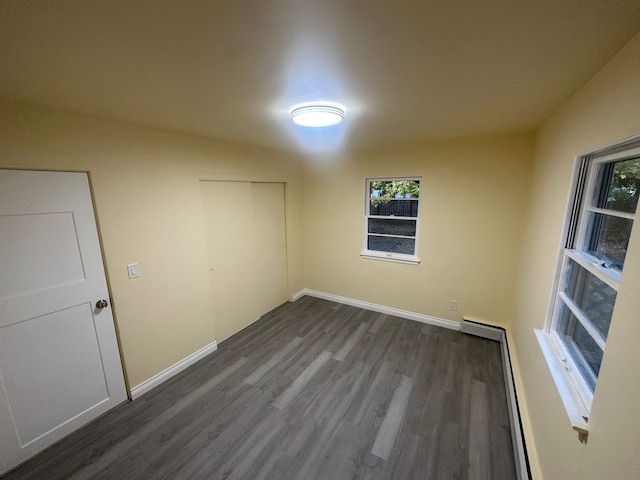 empty room with hardwood / wood-style flooring and a baseboard heating unit