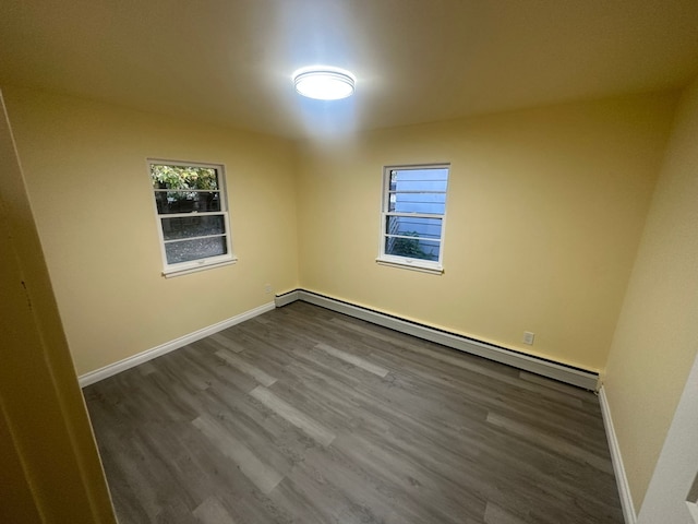 empty room with hardwood / wood-style floors and a baseboard heating unit