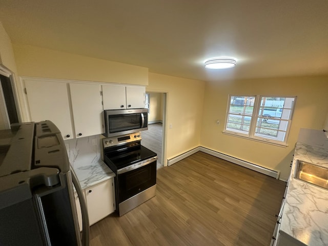 kitchen with sink, stainless steel appliances, dark hardwood / wood-style floors, a baseboard heating unit, and white cabinets