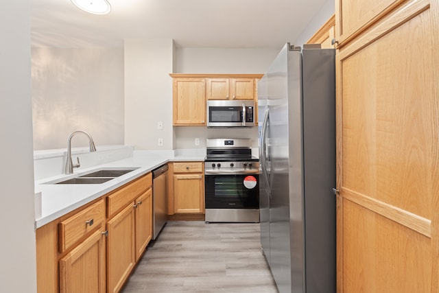 kitchen with appliances with stainless steel finishes, light brown cabinets, light hardwood / wood-style floors, and sink