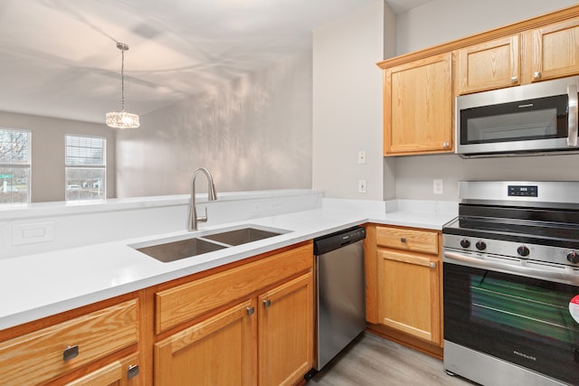 kitchen with sink, hanging light fixtures, light wood-type flooring, light brown cabinetry, and stainless steel appliances