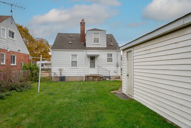 rear view of property featuring central AC unit and a yard