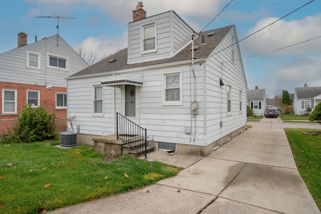 view of front of home with cooling unit and a front yard