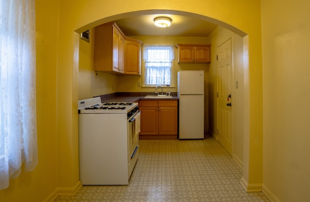 kitchen featuring sink, white appliances, and light brown cabinets