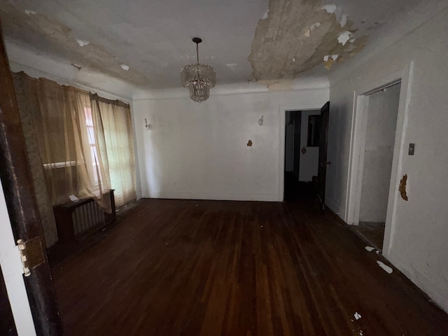 spare room featuring radiator, a chandelier, and dark wood-type flooring