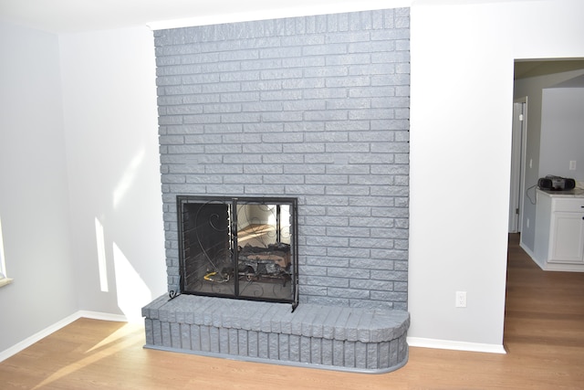 interior details with wood-type flooring and a brick fireplace