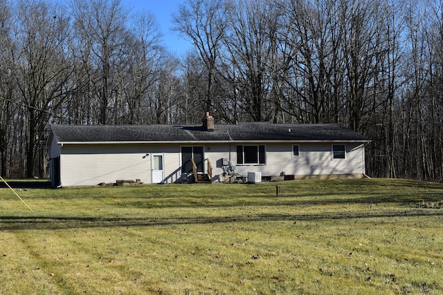 back of house with central air condition unit and a lawn