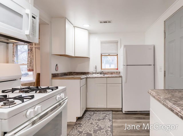 kitchen featuring sink, white cabinets, white appliances, and light hardwood / wood-style flooring