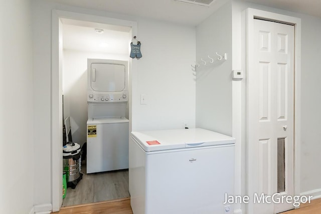 laundry room with stacked washer and dryer and hardwood / wood-style floors