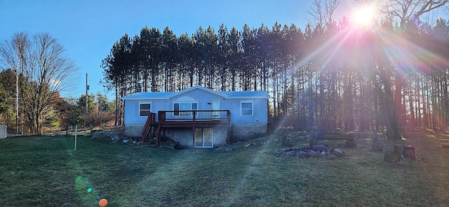 back house at dusk with a deck and a lawn