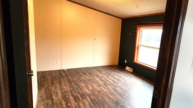 spare room featuring a textured ceiling, dark hardwood / wood-style flooring, and ornamental molding