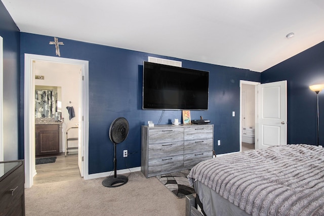 bedroom with light carpet and connected bathroom