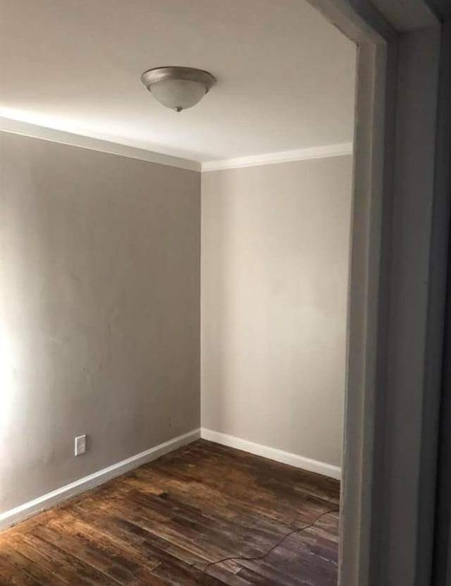 empty room with dark hardwood / wood-style floors and crown molding