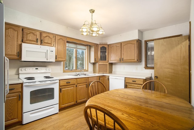 kitchen featuring sink, hanging light fixtures, a chandelier, white appliances, and light hardwood / wood-style floors