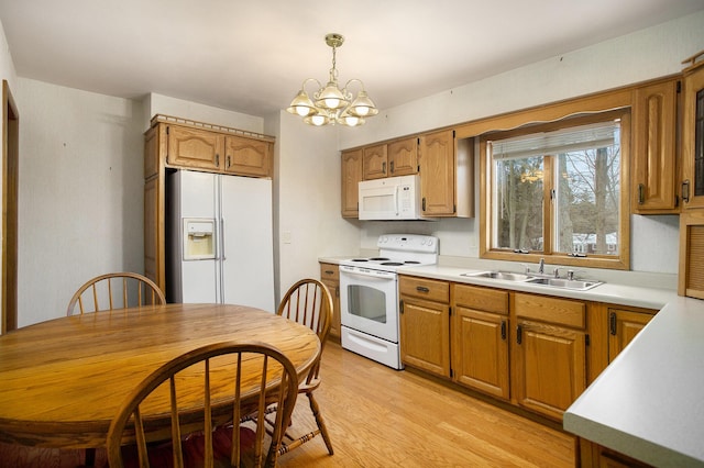 kitchen featuring pendant lighting, white appliances, sink, light wood-type flooring, and a chandelier