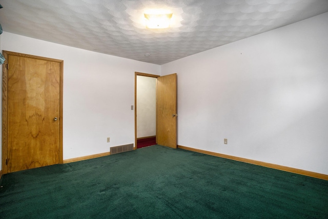 unfurnished room featuring a textured ceiling and dark colored carpet