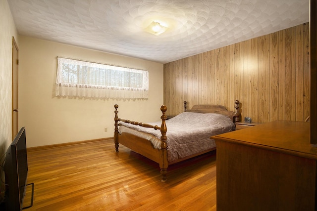 bedroom with wood walls, hardwood / wood-style floors, and a textured ceiling