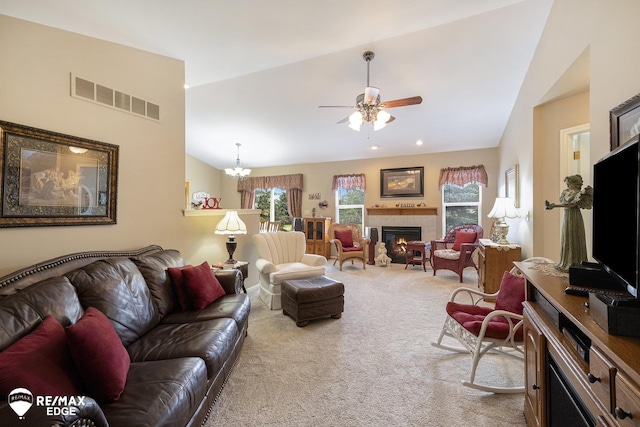 living room featuring a tile fireplace, ceiling fan with notable chandelier, carpet floors, and lofted ceiling