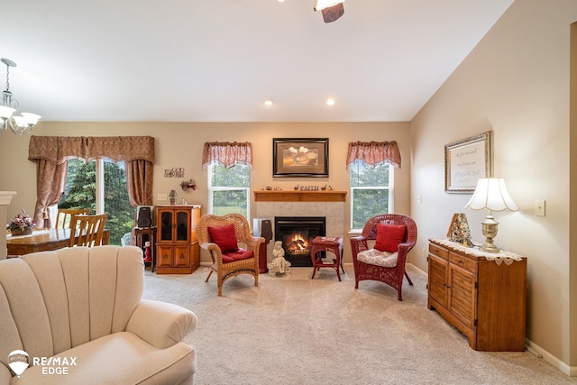 living area featuring light colored carpet, an inviting chandelier, lofted ceiling, and a tiled fireplace