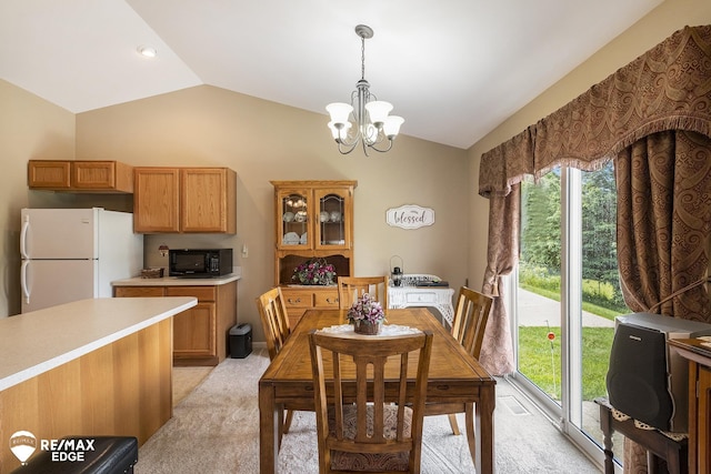 carpeted dining space with an inviting chandelier and lofted ceiling