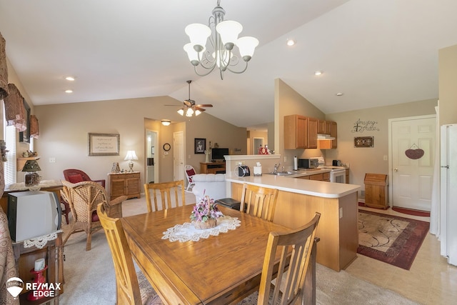 dining space with ceiling fan with notable chandelier, sink, and vaulted ceiling