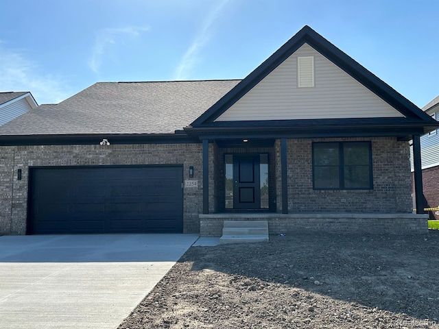 00000 Ozga St, Romulus, MI 48174 - view of front of home with brick siding, an attached garage, driveway, covered porch, and roof with shingles