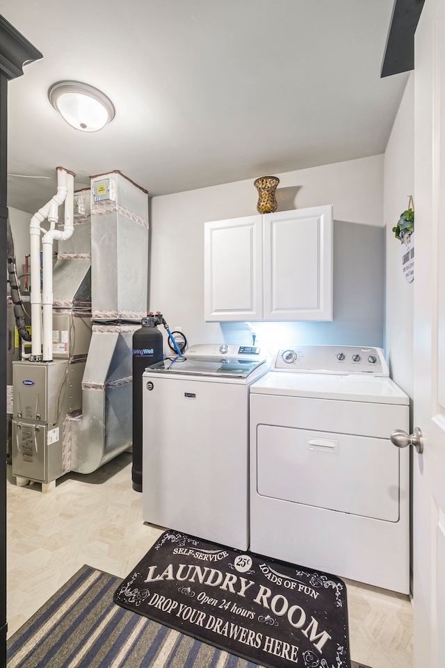 clothes washing area featuring cabinets and washer and clothes dryer