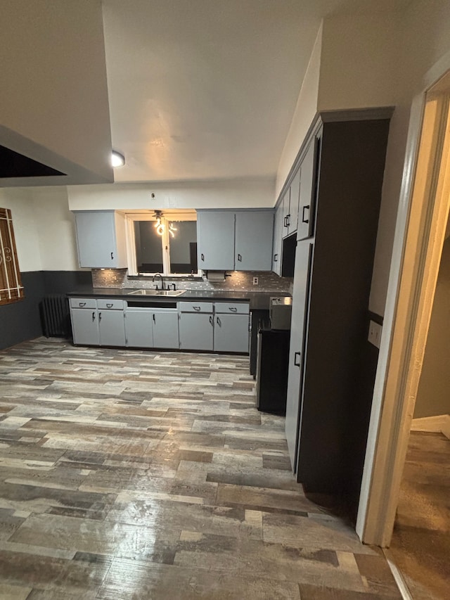 kitchen with decorative backsplash, light wood-type flooring, gray cabinets, and sink